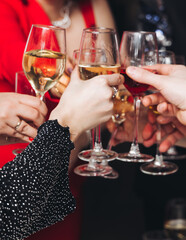 Group of guests celebrate and raise glasses, toasting and cheering with alcohol glasses with wine and champagne in the restaurant on corporate christmas birthday party event or wedding celebration