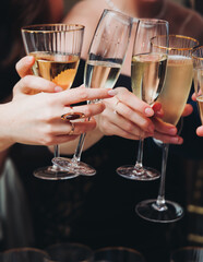 Group of guests celebrate and raise glasses, toasting and cheering with alcohol glasses with wine and champagne in the restaurant on corporate christmas birthday party event or wedding celebration