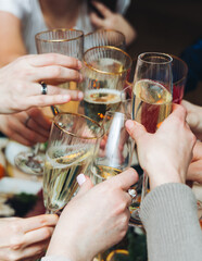 Group of guests celebrate and raise glasses, toasting and cheering with alcohol glasses with wine and champagne in the restaurant on corporate christmas birthday party event or wedding celebration