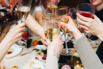 Group of guests celebrate and raise glasses, toasting and cheering with alcohol glasses with wine and champagne in the restaurant on corporate christmas birthday party event or wedding celebration