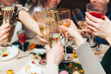 Group of guests celebrate and raise glasses, toasting and cheering with alcohol glasses with wine and champagne in the restaurant on corporate christmas birthday party event or wedding celebration