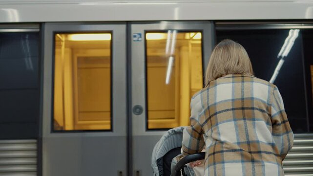 Young mother standing on subway platform, pushing stroller while waiting for train, representing urban family commuting experience
