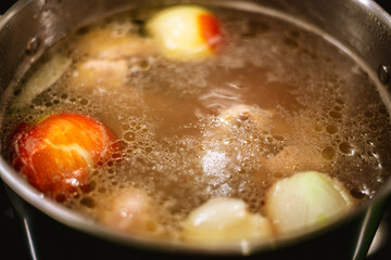 Simmering chicken broth fills the pot on the stove, combining tender pieces of chicken, fragrant onion, creating a rich and comforting stock full of flavor