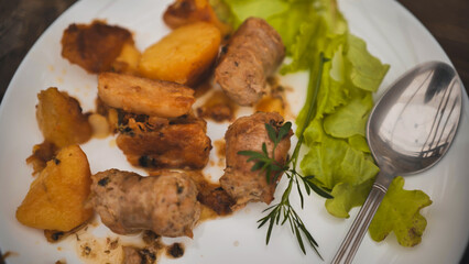 Rustic plate featuring grilled sausage, roasted potatoes alongside crisp green salad, presenting homestyle comfort dining