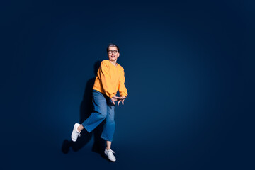 Full length photo of pretty senior female jump shy cute pose wear trendy yellow outfit isolated on dark blue color background
