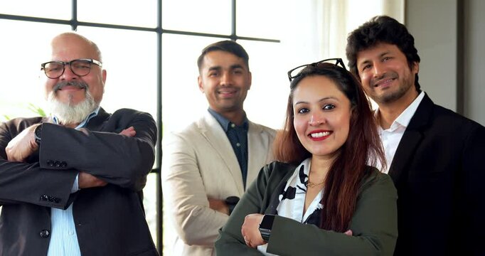 Indian Asian group of confident businessmen or corporate professionals or executives standing with arms folded, smiling, and looking directly at the camera in a modern corporate office environment