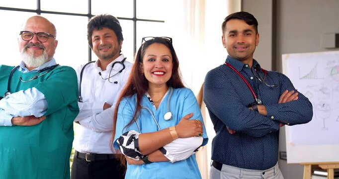 Indian Asian group of doctors and surgeons smiling confidently with folded hands and showing thumbs up while looking at the camera, standing inside a hospital office