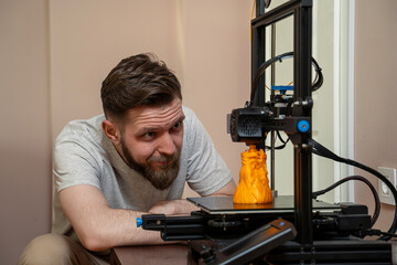 Man looking from close distance how his 3d printer works in his home 