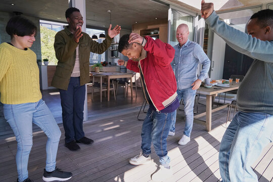 Smiling friends dancing on patio
