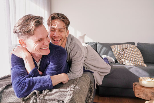Happy gay couple relaxing on sofa