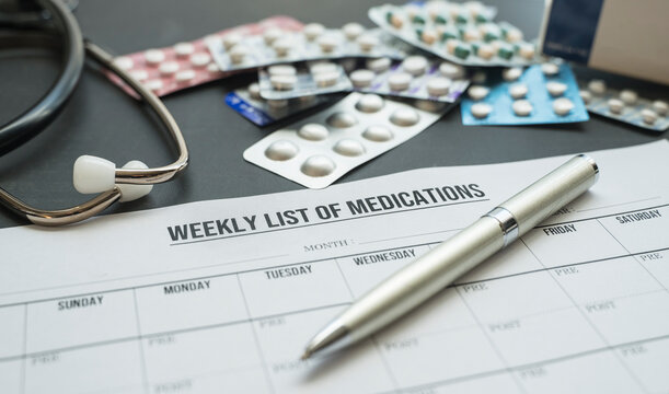 weekly list of medications , pen , stethoscope and assorted medicine blister packs on the table