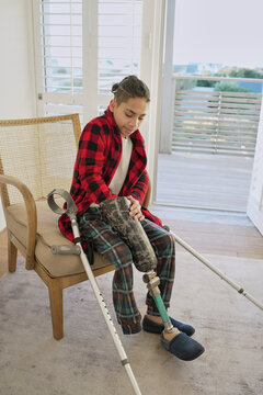 Teenage boy with leg prosthesis sitting on armchair