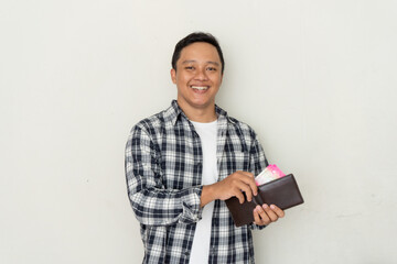 Young Asian man take out his money from the wallet with happy expression. Man smiling while holding his wallet