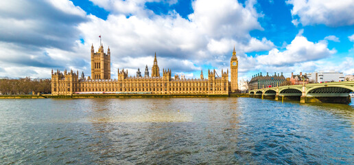 Large picturesque panorama of the famous Palace of Westminster including the Westminster Bridge on a sunny day with a blue sky in London, England.