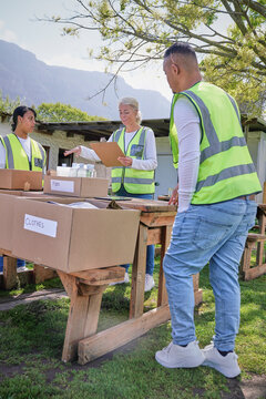 Group of volunteers packaging donation boxes at table outdoors