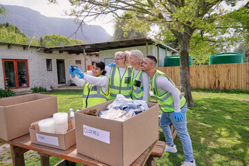 Group of volunteers taking selfie over donation boxes at table outdoors