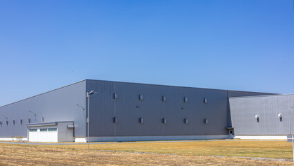 Fototapeta premium Modern Industrial Warehouse Exterior on a Sunny Day, Factory industry, Warehouse Construction in Geometric Modern Design, Backdrop Wall Metal Corrugated Steel Surface Pattern.