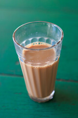 Glass of chai tea on a green table in North India, Asia