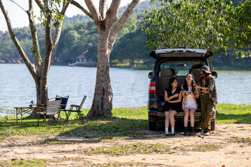 Obraz premium Three women are sitting in a black car by a lake