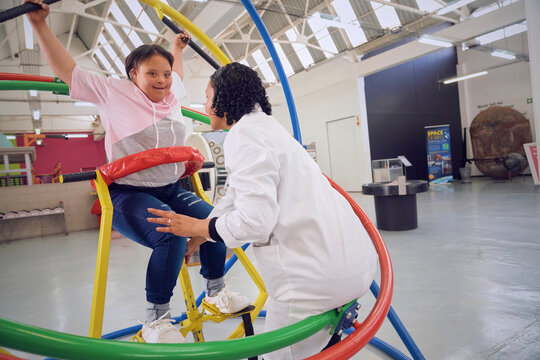 Teenager with down syndrome plying on gyroscope at science center