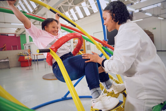 Teenager with down syndrome plying on gyroscope at science center