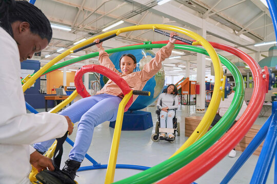 Instructor assisting teenager at gyroscope in science center