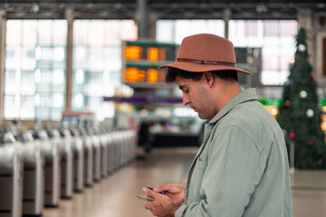 latin Tourist using smartphone while waiting for train at station