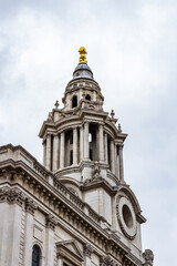 Obraz premium Ornate Bell Tower Architecture with Classical Columns and Gold Accents in Cloudy Sky