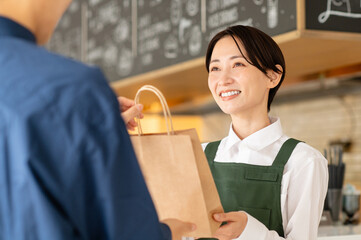 テイクアウト商品を顧客に渡すカフェ店員