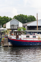 Colorful Boat Docked by Riverside Warehouse in Tranquil Summer Setting