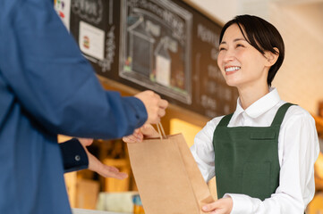 テイクアウト商品を顧客に渡すカフェ店員