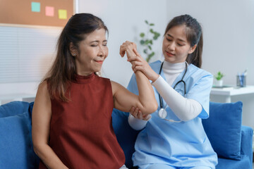 Female doctor examining arm of senior woman during home visit, providing personalized healthcare