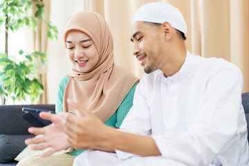 Obraz premium Good looking Asian muslim spouse reading and studying the Holy Koran together in living room.