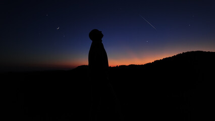 Silhouette of a man and countryside under the stars and Moonlight.