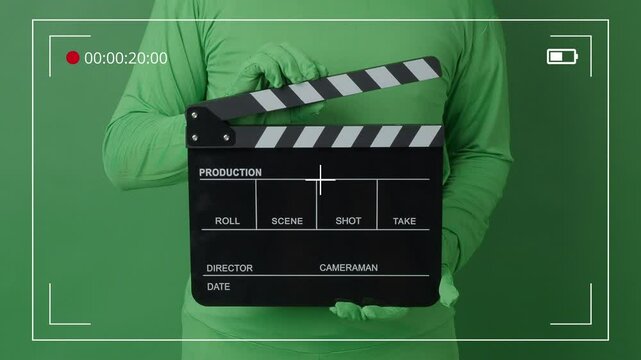 Movie Clapper board clapped by Hands on green screen camera background. Filmmaker hit film slate on green camera frame. Clapperboard Chroma key suit shooting. Green screen composite video production.