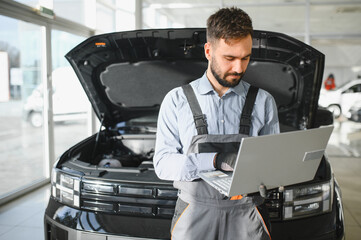 Auto mechanic using computer diagnostic program while repairing car in workshop