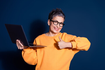 Photo portrait of pretty senior female hold netbook thumb up wear trendy yellow outfit isolated on...
