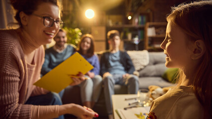 Psychologist laughs with young girl during family therapy session, creating lighthearted and positive atmosphere for emotional growth. Concept of psychology, assistance, therapy