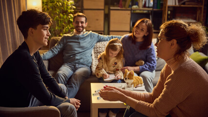 Teenage boy and psychologist warmly communicating during family counseling session, fostering trust...