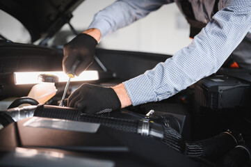 Friendly mechanic in modern car repair shop with car. Professional technician checking vehicle diagnostics and maintenance. Concept of automotive industry and customer service