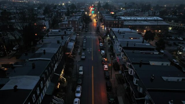 Row of houses and homes on foggy and rainy day in American town. Suburb neighborhood with Main Street in winter. Dusk scene. Descend drone wide shot.