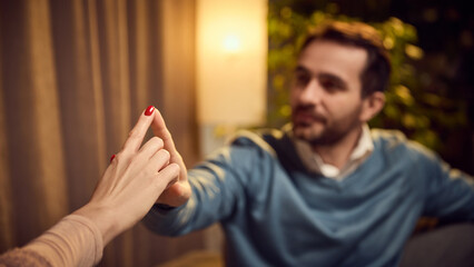 Close-up of psychologist and client touching fingertips, symbolizing trust and connection, with warm lighting and plants in the background. Concept of psychology, assistance, therapy