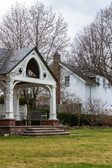 Charming White Cottage with Decorative Gazebo Surrounded by Early Spring Trees