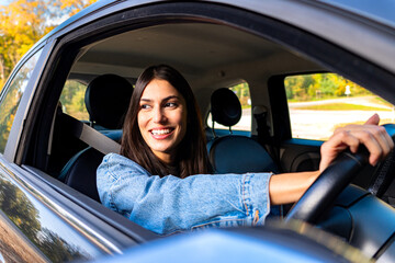 The woman, smiling, drives with the steering wheel on the right side of the car, enjoying the...