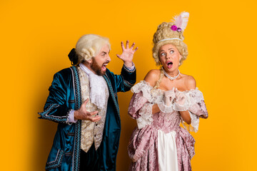Masked couple dressed in vintage attire posing enthusiastically against a bright yellow background...