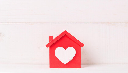 Red House with White Heart Symbol Representing Love and Home on Wooden Background
