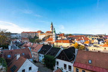 Fototapeta premium Panoramic view of Cesky Krumlov, featuring the historic castle tower and the church of St. John of Nepomuk. The medieval town's charm is beautifully captured on a sunny day