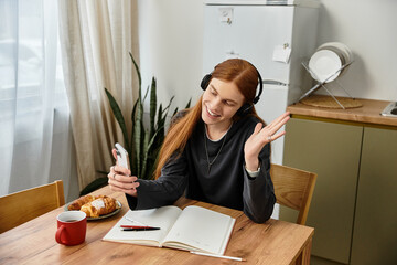 A young guy with long hair is relaxed at home, connecting with friends and sipping coffee.