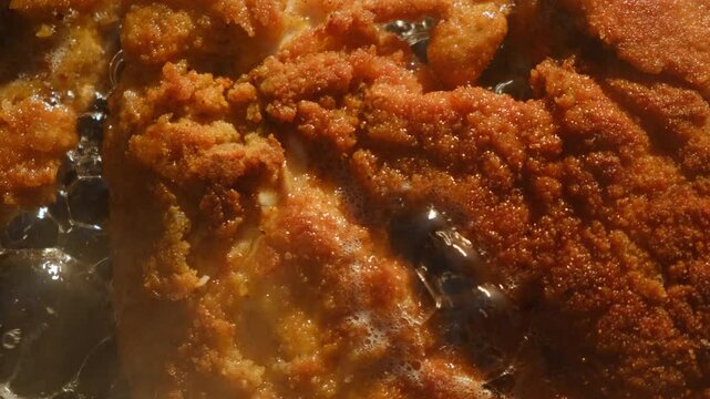 Close up top view of schnitzel frying in hot pan finished to golden crispy skin at nature. Cooking outdoors concept