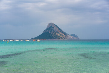 Tavolara island seen from Porto Taverna beach with turquoise water on a cloudy day in Sardinia, Italy